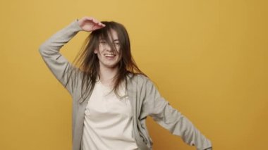 Neşeli Kadın Portresi ellerini oynatmak için ritmik bir şekilde müzik eşliğinde gülümsüyor. Sarı Arkaplanda Zıpla Yavaş Hareket. Dans ediyor, eğleniyor, jestler yapıyor..