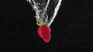Süper yavaş çekimde suya düşen taze çilek meyvesi. Suya düşen taze çilek. Beaty Strawberry suyun içinden geçiyor. Sağlıklı Doğal Vegan Gıda kavramı. Lezzetli Yaz Meyveleri.