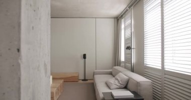 Modern oturma odası. Lüks minimalist tasarım, beyaz ve gri tonlu gerçek daire, zarif sandalye ve lüks mobilyalar, beyaz halı ve siyah ses teknikleri, beton, minimalist tasarım