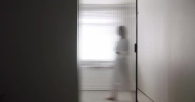 Woman in robes open Transparent sliding door inside the modern bathroom, minimalist bathtub with wood accessories in white and white colors. Modern Minimalist White Bathroom. white minimalist interior