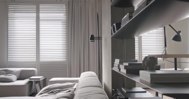 現代のリビングルーム 豪華なミニマリストデザイン 白とグレーの色調の本物のアパート 優雅さの椅子と豪華な家具 白のカーペットと黒のオーディオ技術 コンクリート ミニマリストデザイン — ストック動画