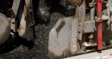 Asphalt paver machine on a road construction site. Road building asphalt paver is laying a new layer of asphalt, Road rollers drive on a new road. Heavy machinery.