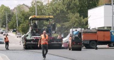 Road Paving on Residential Street. Asphalt laying. Road rollers drive on a new road. Roadway repair. Heavy machinery. Asphalt paver machine on a road construction site.