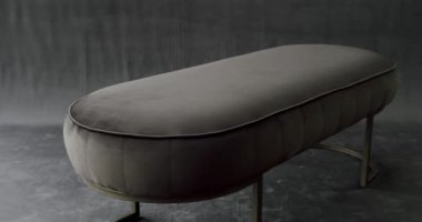 Cosy seat with minimalist pouf. Modern grey Ottoman on grey isolated background. Decor for Luxury apartment. Comfortable white fabric pouf. Elegant grey and brown puff.