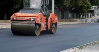 Road building asphalt paver is laying a new layer of asphalt, Road rollers drive on a new road. Asphalt paver machine on a road construction site.