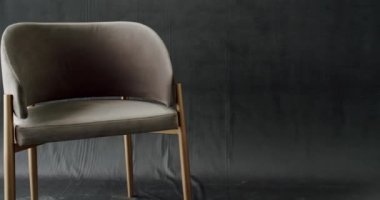 Beige minimalist chair on modern isolated gray background. Comfortable and cosy Chair.Truck shot of interior detail design of modern white beige chair at home. Home sitting on modern relaxing armchair