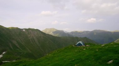 Mountain hills during sunset, Camping and rest after the hike. rest of one person in nature, in the mountains. Tent on the mountain hills. Tourist near his tent in spring mountains.