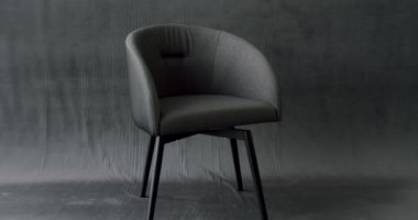 Home sitting on modern relaxing armchair. Truck shot of interior detail design of modern chair at home. Gray minimalist chair on modern isolated gray background. Comfortable and cosy Chair.
