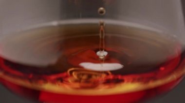 Luxury brandy and drop in glass of cognac. Glass with golden cognac on isolated black background with smoke. Brandy, cognac, and whisky. Slow motion. Luxury Drink Whisky with smoke.