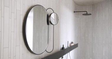 Modern Interior with round mirror, minimalist interior in white colors with bathroom accessories , mirror and lamp in modern interior. Modern White Bathroom. Elegance Design Interior.