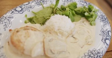 Mediterranean and French cuisine. Chicken fillet with mushroom sauce with rice and salad leaves served on a plate in a modern restaurant. french food.