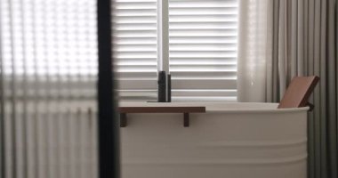 Luxury Bathroom Interior, minimalist interior in white colors with bathroom accessories , white bathtub, bathtub modern design. Luxury cozy white Apartment with transparent sliding door.