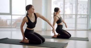 Siyah aktivite kıyafetli kadınlar yoga sınıfında minder üzerinde yoga asanas dansı yapıyorlar. 