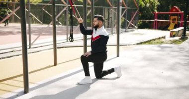 Attractive fitness man does exercising outside. Gym health outside concept. Trainer male correcting fit does gym exercises with rubber band . Outdoor Athletic man does exercises with elastic band.