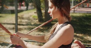 Lastik bantlı kişisel antrenörle açık hava eğitimi. Dışarıda egzersiz yapan genç bir kız. Egzersiz yapan bir kadın. Spor salonu sağlığı konseptin dışında. Antrenör erkek formda kadın jimnastik yapıyor..