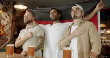 Word Cup Supporters. Men with the flag of the national country of Germany drinking beer and watching sport game. World Cup, football, hockey, basketball, Loyal football fans supporting their team.