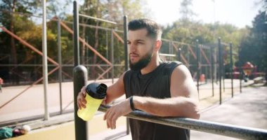 Young aspiring bodybuilder resting after warm-up. End of workout, good job. A fit Caucasian man relaxing after training. Sports and fitness technology. Healthy lifestyle and outdoor training