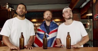 Fans watching football in a bar with friends. Soccer fans celebrating victory of team in sports bar Loyal football fans supporting their team.Men with the flag of the national country of Great Britain