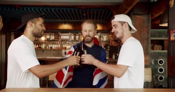 世界杯的支持者 混合种族的快乐支持者在获胜后欢呼和欢呼 酒吧里的朋友们玩得很开心拿着大不列颠国旗的男人喝啤酒 — 图库视频影像