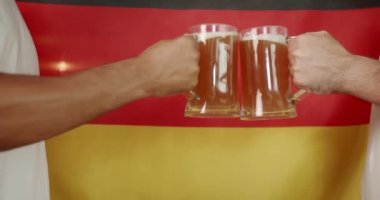 Young Peoples hands clash like glasses full of beer against the background of Germany. Soccer fans celebrating victory of team in sports bar. Friends in a Pub. Word Cup Supporters.