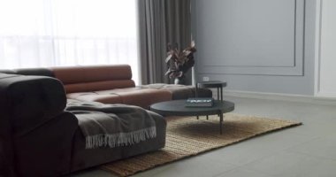 Gri ve kahverengi mobilyalı modern Minimalist oturma odası. Köşedeki kanepe ve yuvarlak masalı lüks Modern Ev İçi. Samimi Modern Mobilya Tasarımı. Lüks Zarif Oda