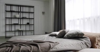 Minimalist İskandinav tarzı iç mekan. Kral yatağı olan şık bir yatak odası. İçi beyaz duvarlarda raflarla dolu. Mobilyalı lüks bir yatak odası. Zarif beyaz ve kahverengi iç tasarım.