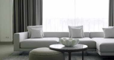 Minimalist oturma odası, beyaz mobilyalar ve yuvarlak masa. Köşedeki kanepe ve kitaplığı olan lüks modern ev iç mimarisi. Moda mobilyalar. Minimalist İç İşleri. Konforlu Modern Mobilya Tasarımı.