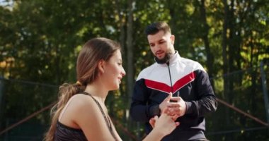 Antrenör erkek, formda kadın egzersizleri yapıyor. Kişisel antrenörle açık hava eğitimi. Sportif erkek ve kadın kalçalarının kaslarını ve kalçalarını güçlendirmek için tek ayak üzerinde hamle yapıyorlar..