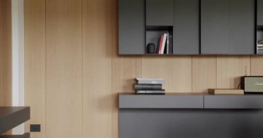 Ahşap duvarlı ve gri mobilyalı minimalist oturma odası. Köşedeki kanepe ve kitaplığı olan lüks modern ev iç mimarisi. Moda mobilyalar. Rafları ve kitabı olan rahat Modern Mobilya Tasarımı.