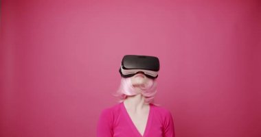 Kadın sanal gerçeklik gözlüğü kullanıyor, izole edilmiş pembe arka planda sanal hayatta dokunma ve arama yapıyor. Gelecek kavramı, yenilik, teknoloji, oyun, yaşam tarzı, eğlence. Pembe renkler. Modern Kadın