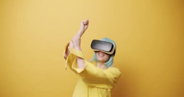 Genç bir kadın oyun oynamak için yenilikçi teknoloji VR gözlükleri kullanıyor ve sanal gerçekliğin 360 VR kulaklığını kullanarak rahatlıyor. Gelecek kavramı, yenilik, teknoloji, oyun, yaşam tarzı.