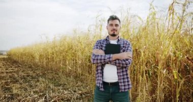 Tarlada poz veren genç bir çiftçi. Tarım sektörü kavramı. İşletme tarım hasat konsepti. Kalite kontrol yeşil süpürge çiftliği. yeşil buğday hasadı mikrop tarım endüstrisi.