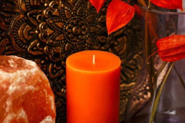 Rafta aromatik turuncu mum ve diğer dekoratif eşyalar var. Resmi kapat