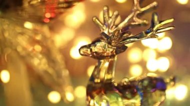 Arka planda bir Noel çelenginin parıltısı. Cam geyik şeklinde bir Noel süslemesi.