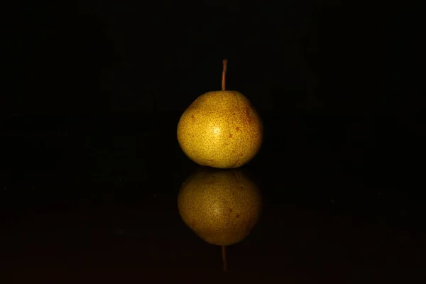 Une poire jaune sur fond noir — Photo