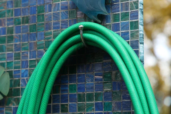 Green hose for watering plants in the garden — Stock Photo, Image