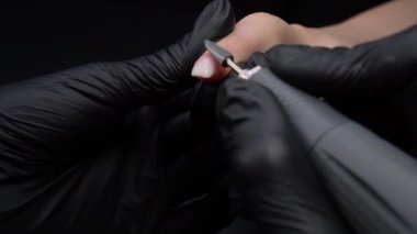 Manikür üzerinde çalışıyorum, yakın çekim. Güzellik salonu elleri ve tırnakları koyu bir arka planda. Video görüntüleri