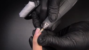 Manikür üzerinde çalışıyorum, yakın çekim. Güzellik salonu elleri ve tırnakları koyu bir arka planda. Video görüntüleri