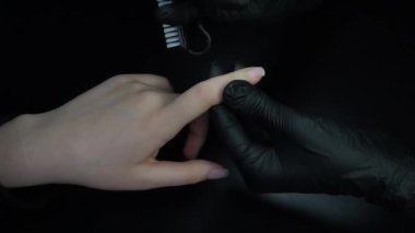 Manikür üzerinde çalışıyorum, yakın çekim. Güzellik salonu elleri ve tırnakları koyu bir arka planda. Video görüntüleri
