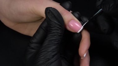 Manikür üzerinde çalışıyorum, yakın çekim. Güzellik salonu elleri ve tırnakları koyu bir arka planda. Video görüntüleri