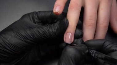 Manikür üzerinde çalışıyorum, yakın çekim. Güzellik salonu elleri ve tırnakları koyu bir arka planda. Video görüntüleri
