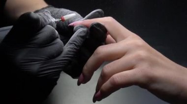 Siyah eldivenli bir kadının güzellik salonunda manikür üzerinde çalışmasını yakından izleyeceğiz.