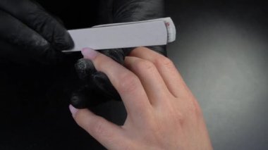 Siyah eldivenli bir kadının güzellik salonunda manikür üzerinde çalışmasını yakından izleyeceğiz.