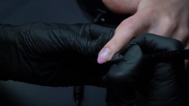 Siyah eldivenli bir kadının güzellik salonunda manikür üzerinde çalışmasını yakından izleyeceğiz.