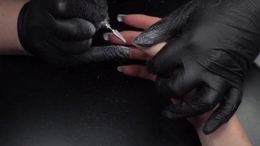 Manikür üzerinde çalışıyorum, yakın çekim. Güzellik salonu elleri ve tırnakları koyu bir arka planda. Video görüntüleri