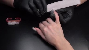 Manikür üzerinde çalışıyorum, yakın çekim. Güzellik salonu elleri ve tırnakları koyu bir arka planda. Video görüntüleri