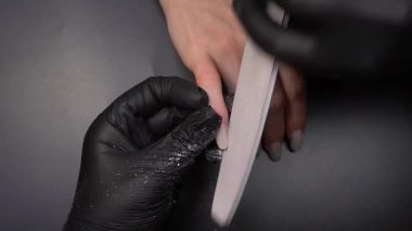 Manikür üzerinde çalışıyorum, yakın çekim. Güzellik salonu elleri ve tırnakları koyu bir arka planda. Video görüntüleri