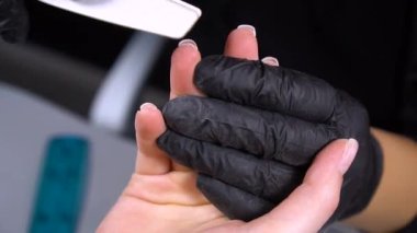 Manikür yaptırmaya çalışıyorum. Güzellik salonu elleri ve tırnakları koyu bir arka planda. Video görüntüleri