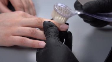 Kadın tırnaklarını törpülemek ve genç bayan için manikür yapmak için siyah eldivenler kullanıyor. Güzellik salonu kavramı, manikür, vücut bakımı, sanat
