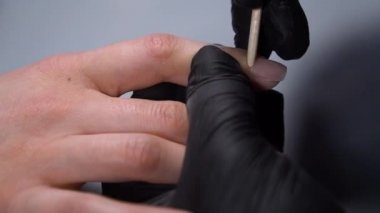 Siyah eldivenli bir kadının güzellik salonunda manikür üzerinde çalışmasını yakından izleyeceğiz.